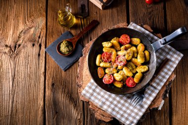 Yeşil pesto ve kiraz domates ahşap arka plan üzerinde pişmiş gnocchi