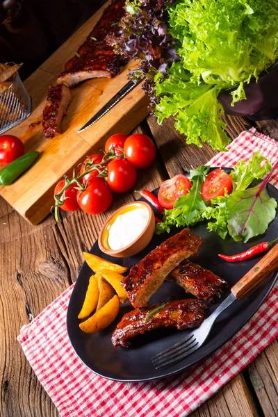 Barbekü kaburga plaka yeşil salata ve beyaz sos ile.