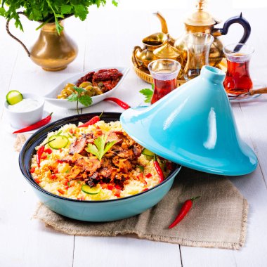 Beyaz arka planda kuskus, sebze ve etli Tajin.