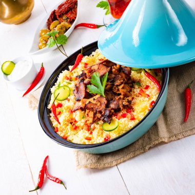 Beyaz arka planda kuskus, sebze ve etli Tajin.