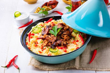 Beyaz arka planda kuskus, sebze ve etli Tajin.