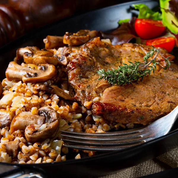 Bife de porco com cogumelos e grumos de trigo mourisco e salada de manga — Fotografia de Stock