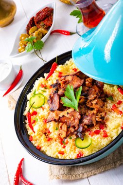 Beyaz arka planda kuskus, sebze ve etli Tajin.