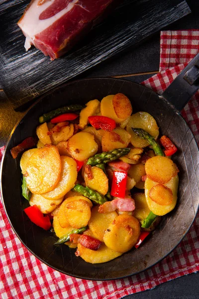 Жареный картофель с копченым беконом, зеленой спаржей и паприкой. — стоковое фото