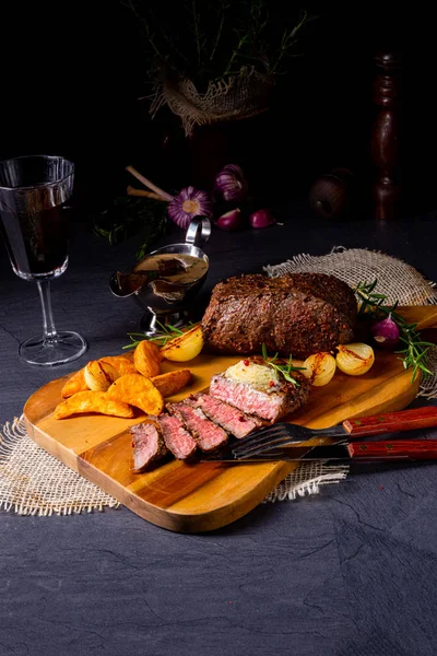 Bife de carne de manteiga média rústica com ervas e fatias de batata — Fotografia de Stock