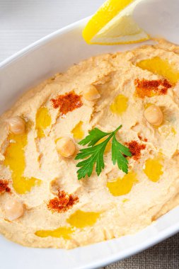 Beyaz arka planda limon ve biberli humus ezmesi.