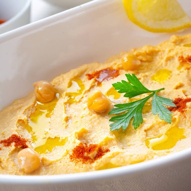 Beyaz arka planda limon ve biberli humus ezmesi.