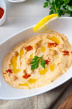 Beyaz arka planda limon ve biberli humus ezmesi.