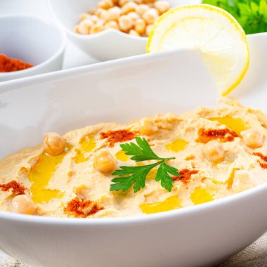 Beyaz arka planda limon ve biberli humus ezmesi.