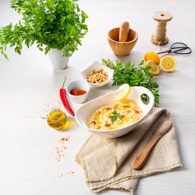 Beyaz arka planda limon ve biberli humus ezmesi.