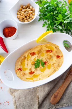 Beyaz arka planda limon ve biberli humus ezmesi.