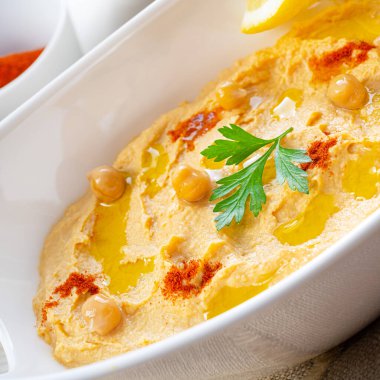Beyaz arka planda limon ve biberli humus ezmesi.