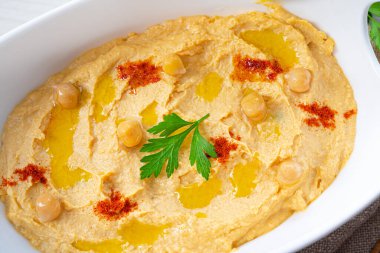 Beyaz arka planda limon ve biberli humus ezmesi.