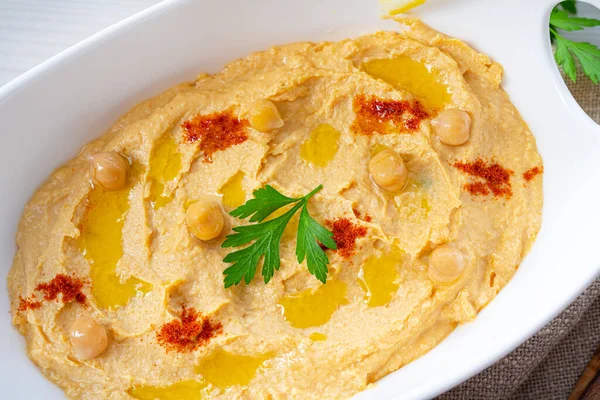 Beyaz arka planda limon ve biberli humus ezmesi.