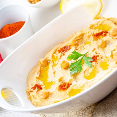 Beyaz arka planda limon ve biberli humus ezmesi.