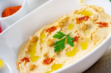 Beyaz arka planda limon ve biberli humus ezmesi.