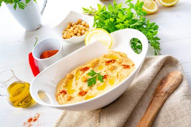 Beyaz arka planda limon ve biberli humus ezmesi.