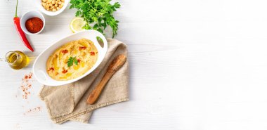 Beyaz arka planda limon ve biberli humus ezmesi.