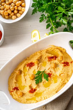Beyaz arka planda limon ve biberli humus ezmesi.