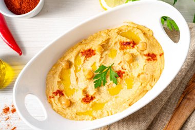 Beyaz arka planda limon ve biberli humus ezmesi.