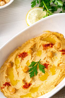 Beyaz arka planda limon ve biberli humus ezmesi.