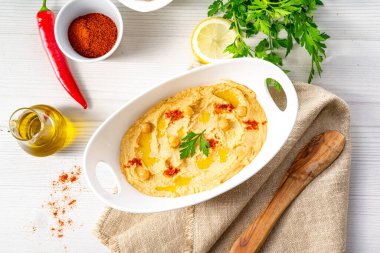 Beyaz arka planda limon ve biberli humus ezmesi.
