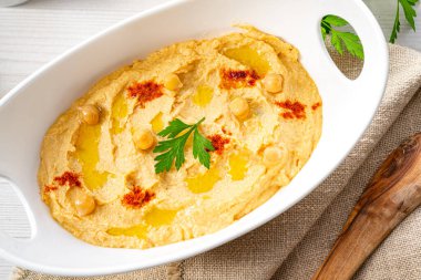 Beyaz arka planda limon ve biberli humus ezmesi.