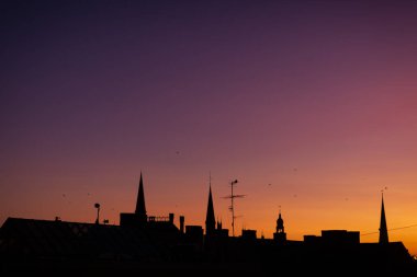 Gün batımında şehrin çatılarının profili