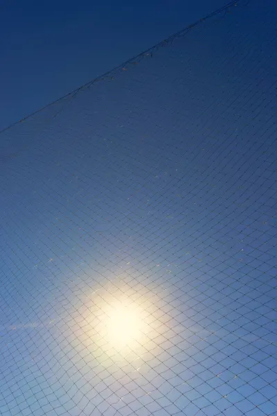 Die Sonne scheint durch das Netz gegen den Himmel — Stockfoto