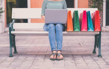Kırpılan atış için online alışveriş dizüstü bilgisayar açık bir bankta kullanan kadın