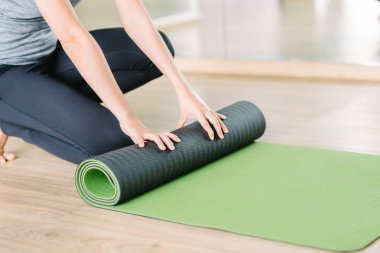 Yeşil yoga mat haddeleme kadın görüntüsünü kırpılmış 
