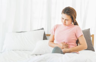 Asya genç kadın mide sancısı tutan yatakta oturuyordu