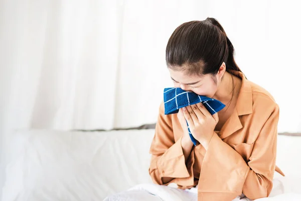 Asian woman using handkerchief to sneeze with eye close in bedroom room and feeling sick or allergy to something