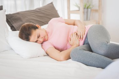 Mide sancısı tutan yatakta yatan hasta Asyalı Genç kadın