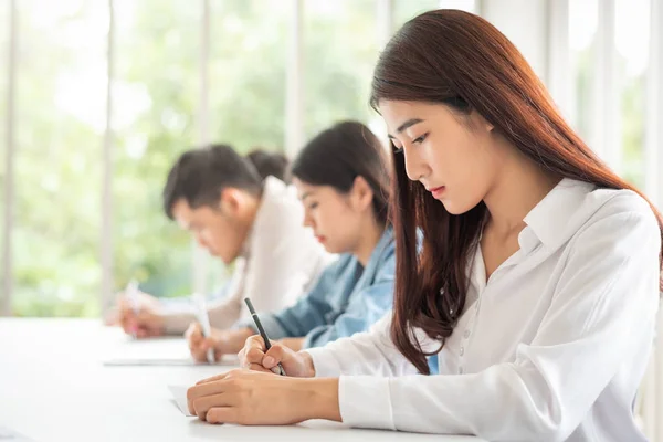 Genç Asyalı kadın sınıf odasında bir test olan bir satır da oturan