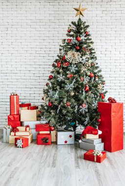Beyaz tuğlalı arka planda hediye kutusu olan Noel ağacı