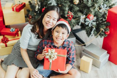 Asyalı kadın ve çocuk Noel tatilinde hediye kutusuyla iyi vakit geçiriyorlar.