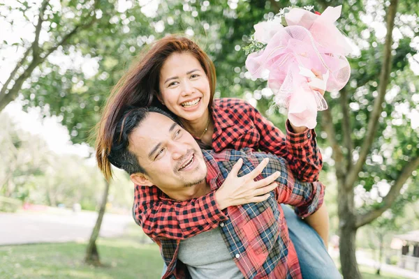 Homem Asiático Dando Piggyback Para Sua Namorada Com Buquê Flores — Fotografia de Stock