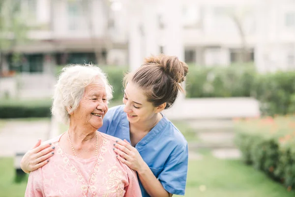微笑的护士照顾者与亚洲老年妇女户外在公园 — 图库照片
