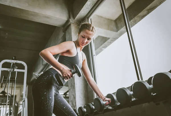 Woman working out at gym doing dumbbell row — Stock Photo, Image