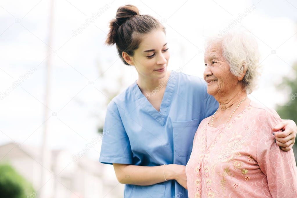 Caregiver with Asian elderly woman outdoor