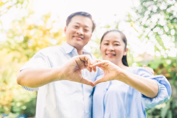 Pareja mayor haciendo gesto de forma de corazón —  Fotos de Stock