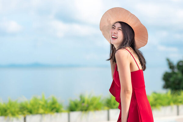 Asian woman in red dress enjoys her vacation in sunny day