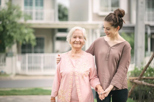 Mujer caminando y abrazando mujer anciana asiática —  Fotos de Stock