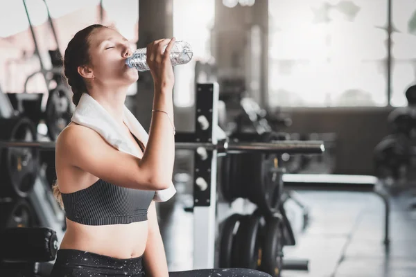 Woman drinking water from bottle after workout — Stock Photo, Image