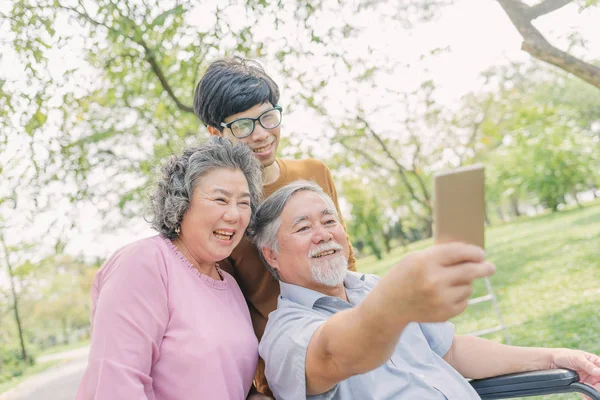 Senior asiático hombre usando smartphone para selfie con su familia —  Fotos de Stock