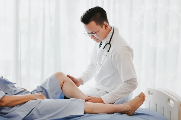 Médico examinando seu joelho paciente na cama no hospital — Fotografia de Stock