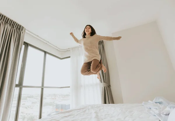 Glückliche Frau aufgeregt springt auf ihr Bett — Stockfoto