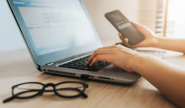 Hand med mobiltelefon och bärbar dator — Stockfoto