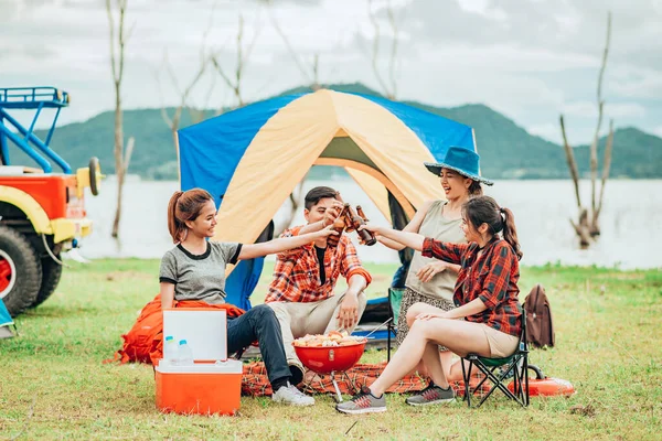 Bir grup arkadaş barbekü yapıyor ve bir şişe bira içiyorlar.